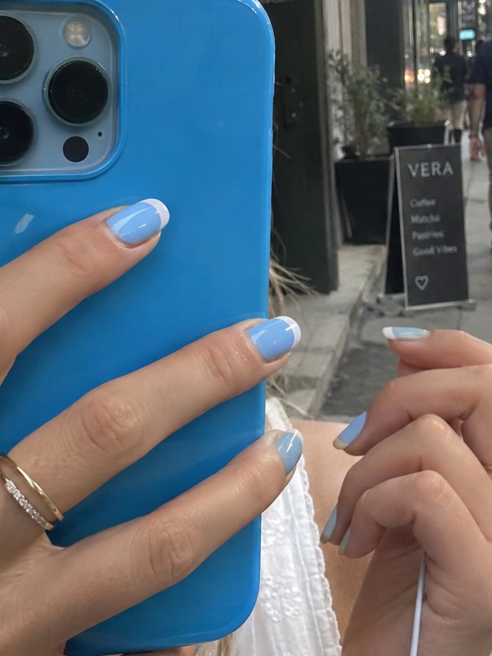 White french tips painted over pale blue polish